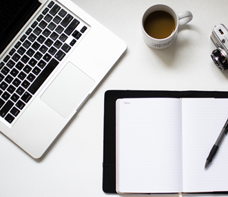 laptop with notebook, cup of tea and small camera
